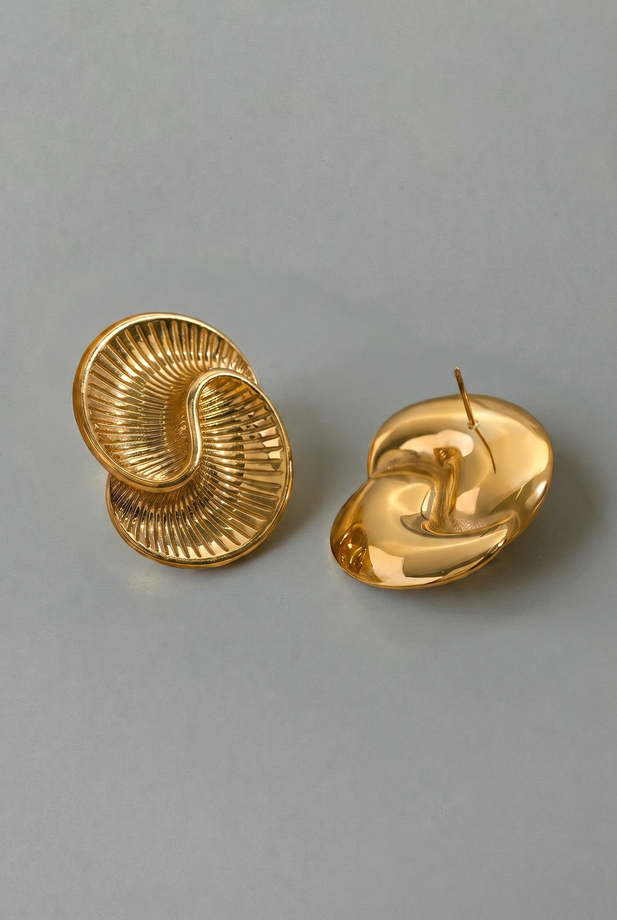 Pair of gold spiral earrings on a gray background