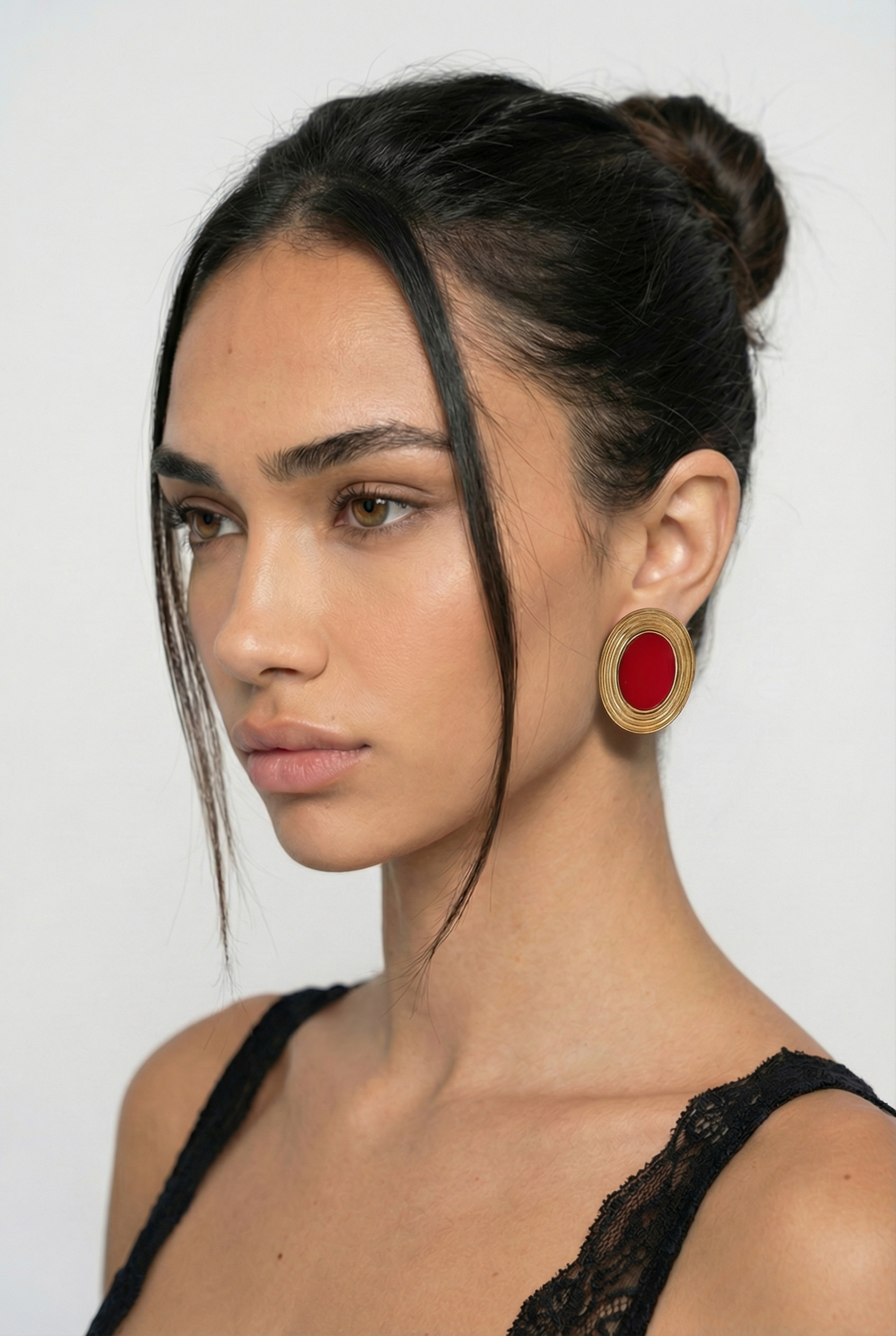 Woman wearing a large red earring against a white background
