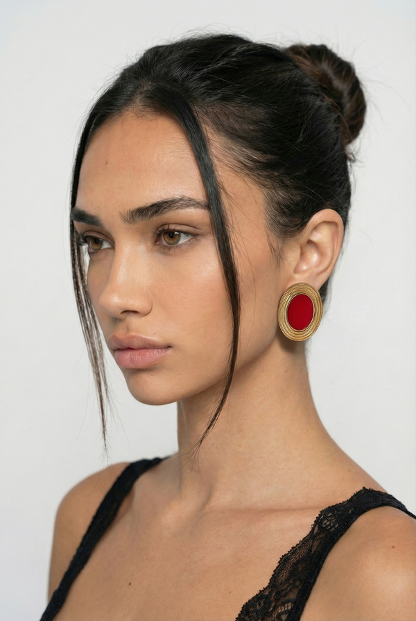 Woman wearing a large red earring against a white background