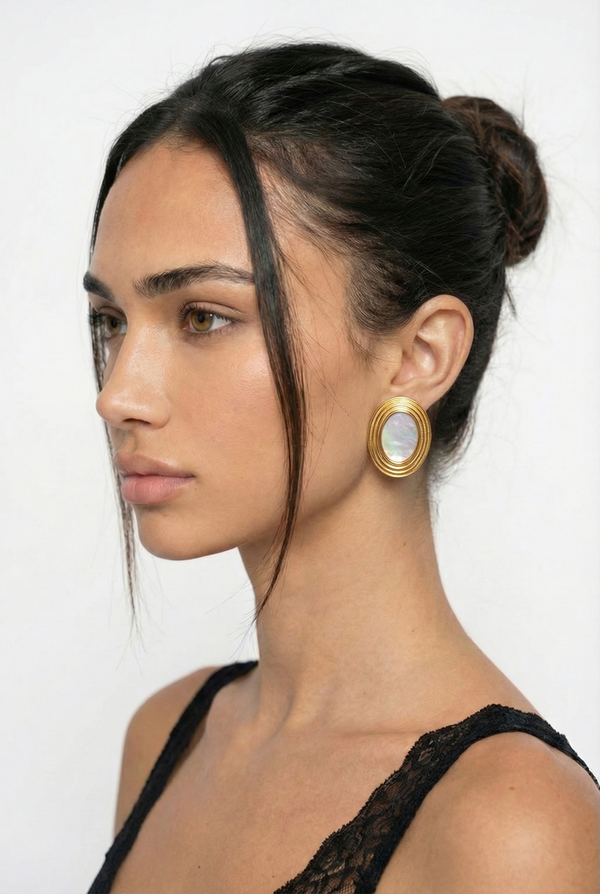 Woman wearing gold earrings with a white background