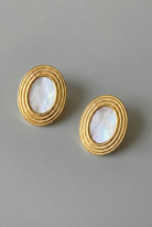 Pair of gold earrings with circular designs on a gray background