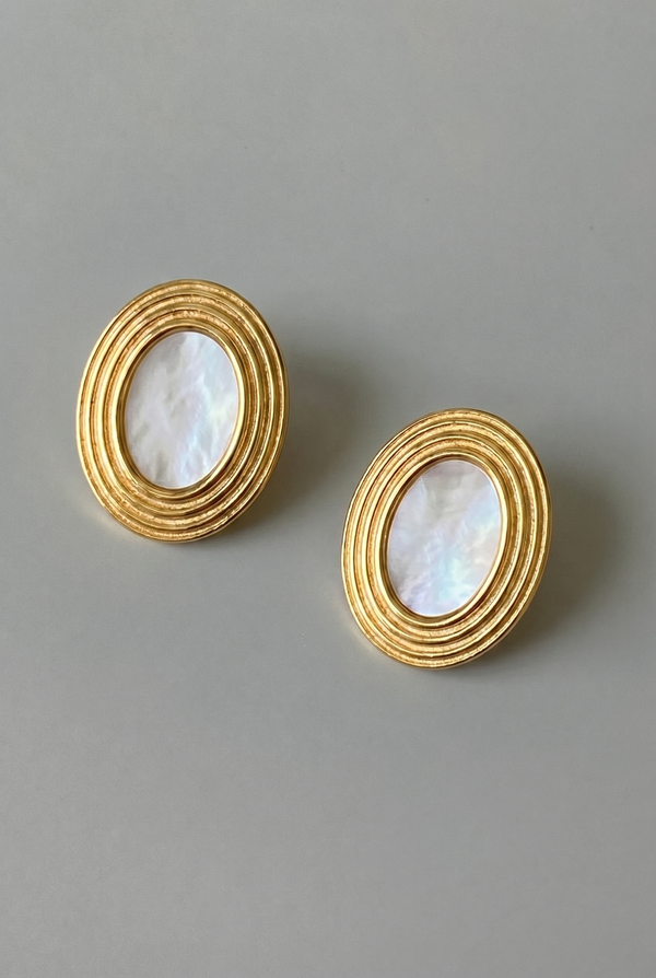 Pair of gold earrings with circular designs on a gray background
