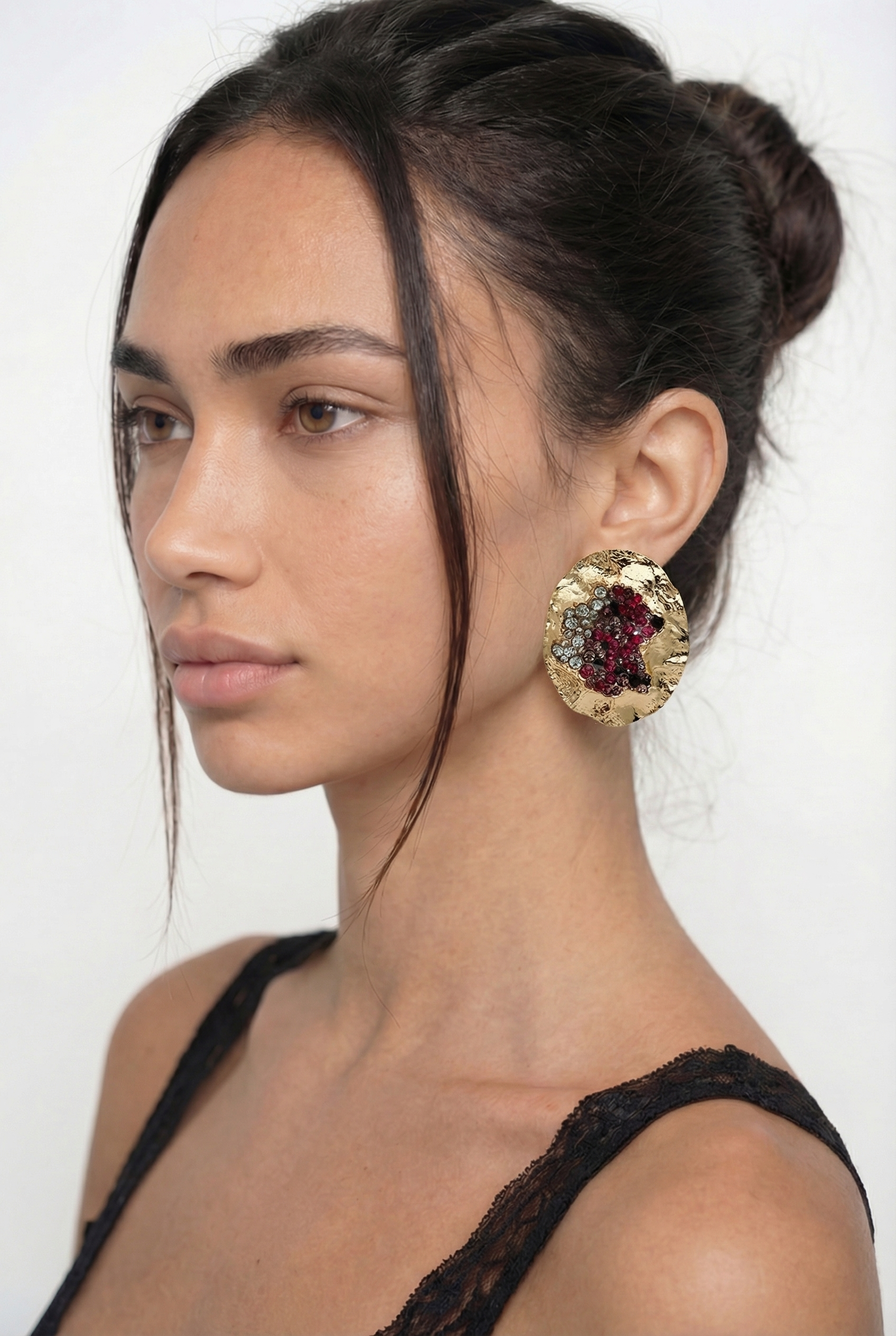 Woman wearing a large, ornate earring on a white background