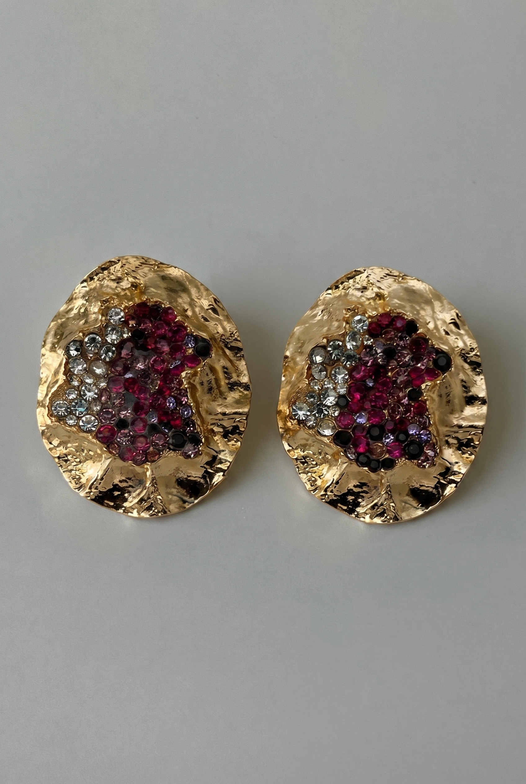 Gold earrings with gemstone accents on a gray background