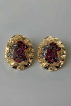 Gold earrings with gemstone accents on a gray background
