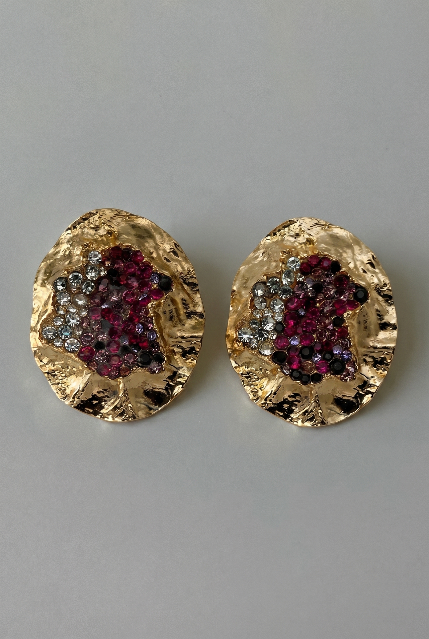 Gold earrings with gemstone accents on a gray background