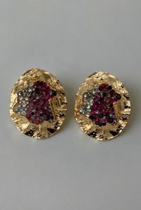 Gold earrings with gemstone accents on a gray background