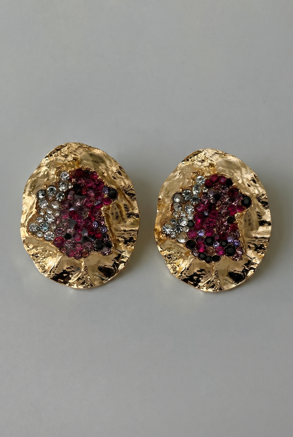 Gold earrings with gemstone accents on a gray background
