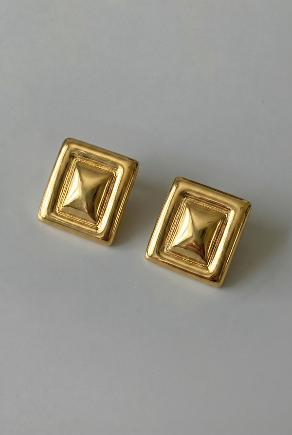 Pair of gold square earrings on a gray background