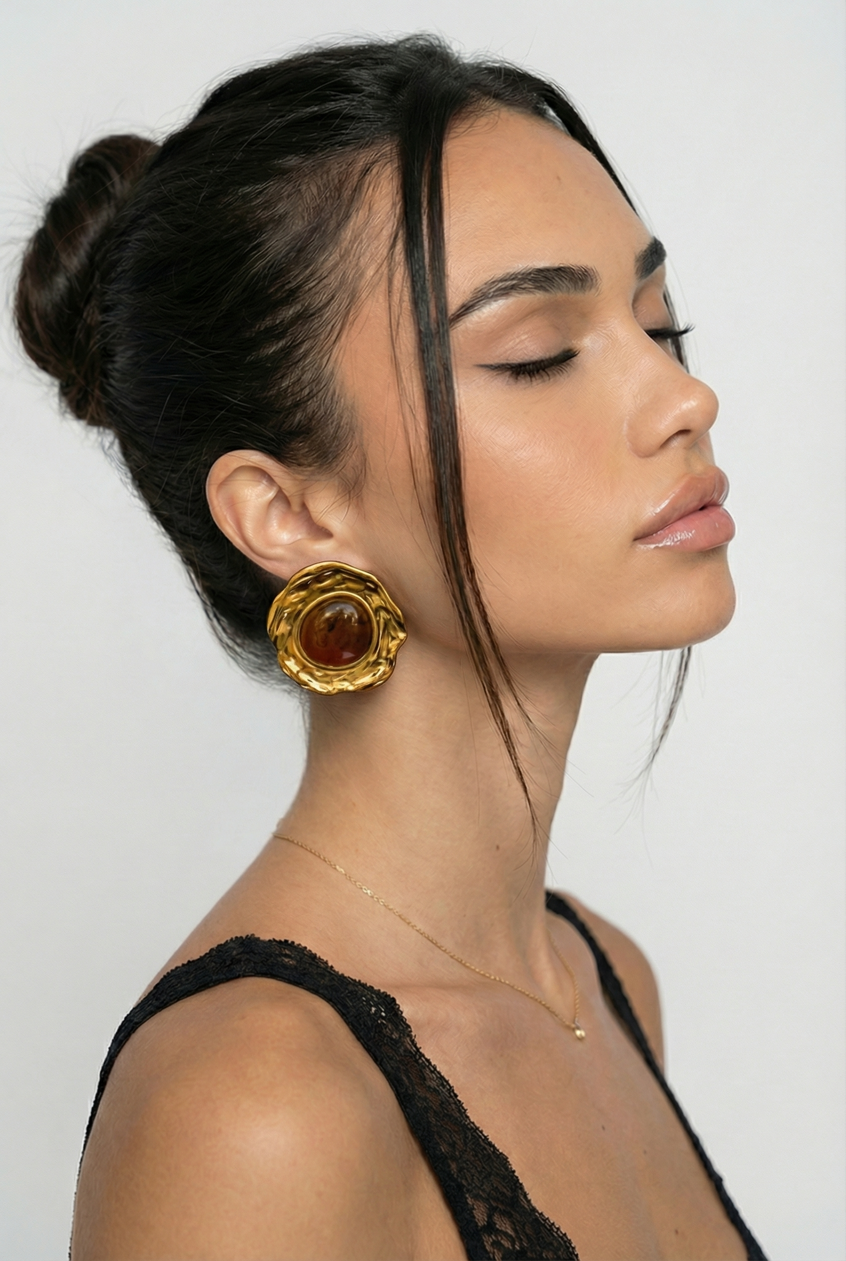 Woman wearing a large gold earring against a plain background