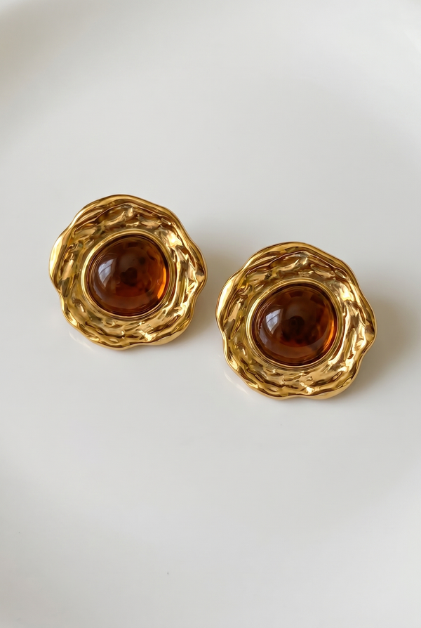 Pair of gold earrings with brown gemstones on a white background