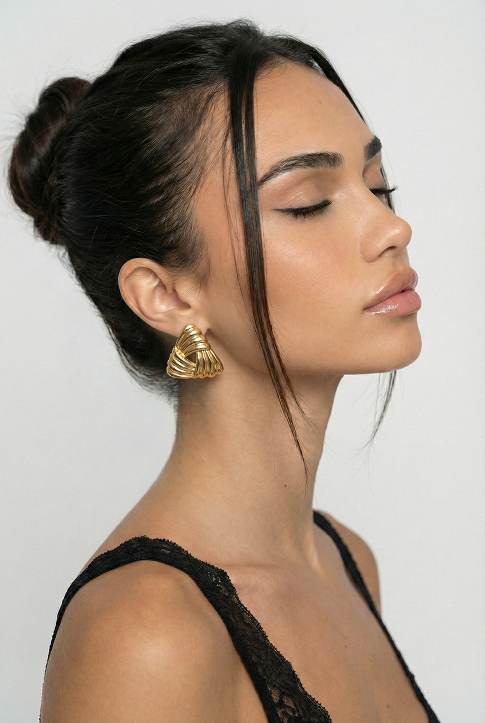 Woman wearing a large gold earring against a plain background