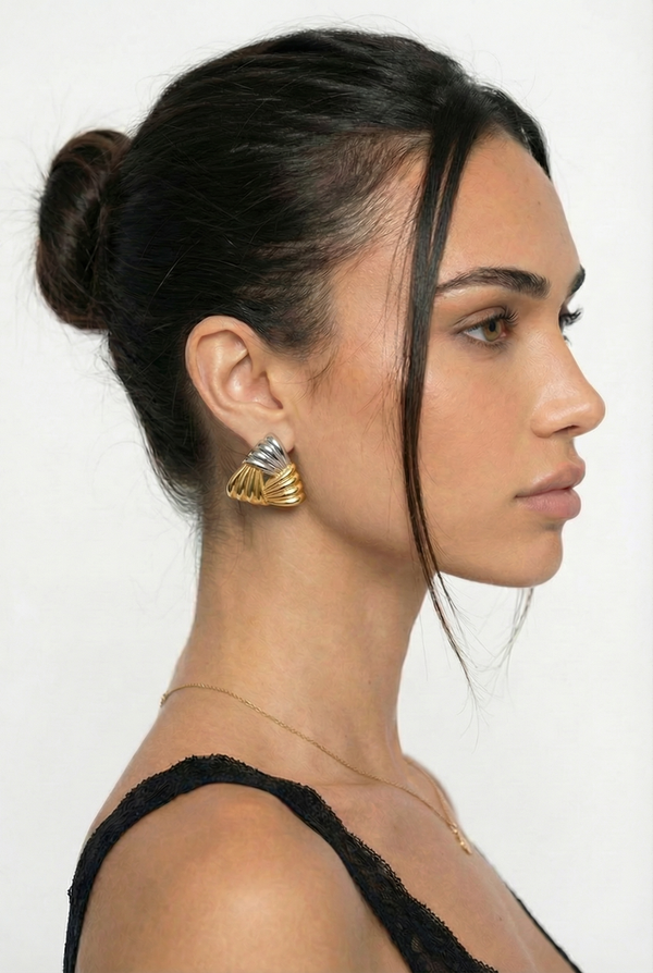 Woman wearing gold earrings with a plain background