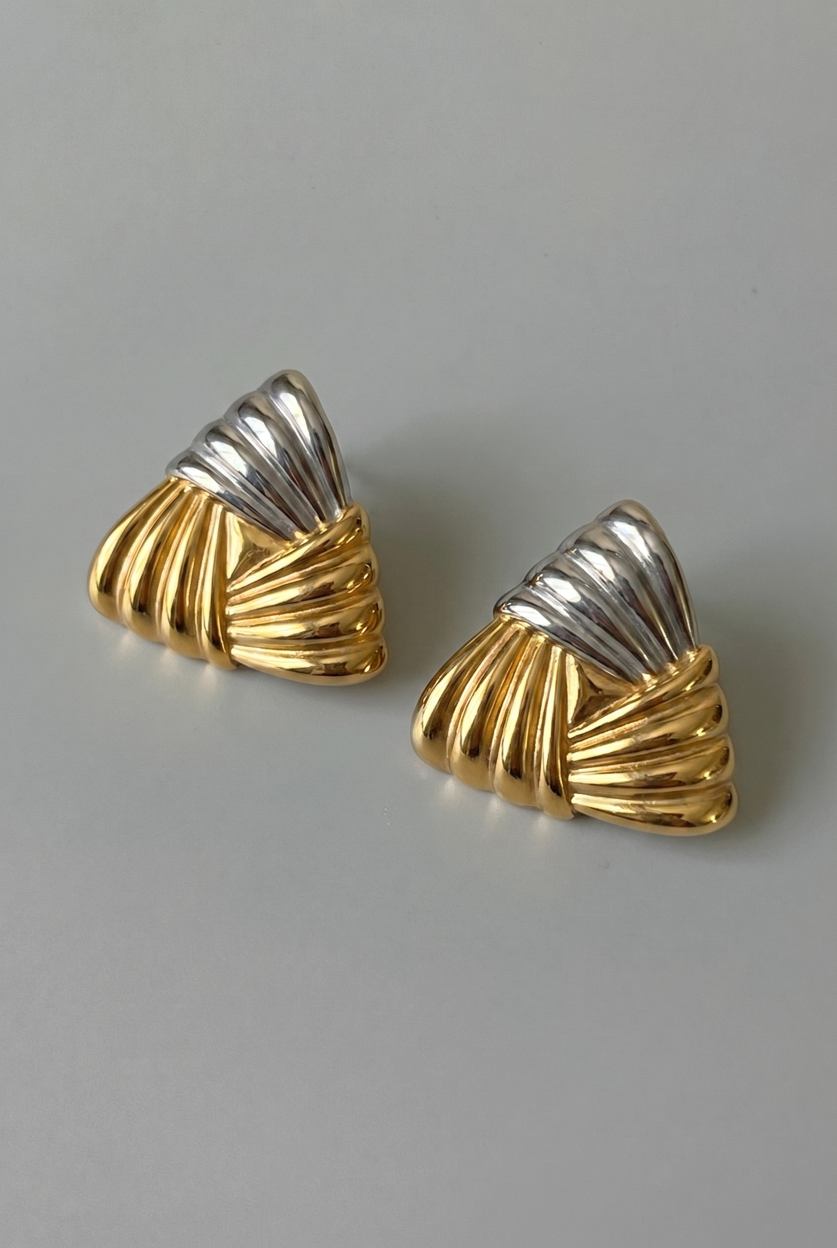 Pair of gold and silver earrings on a gray background