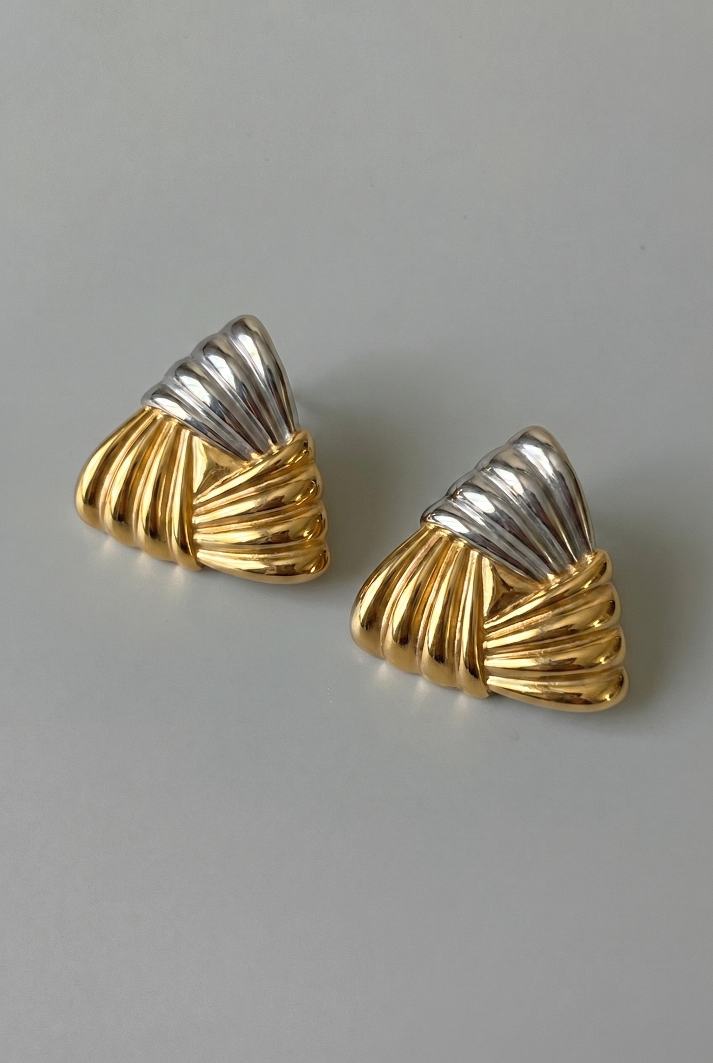 Pair of gold and silver earrings on a gray background