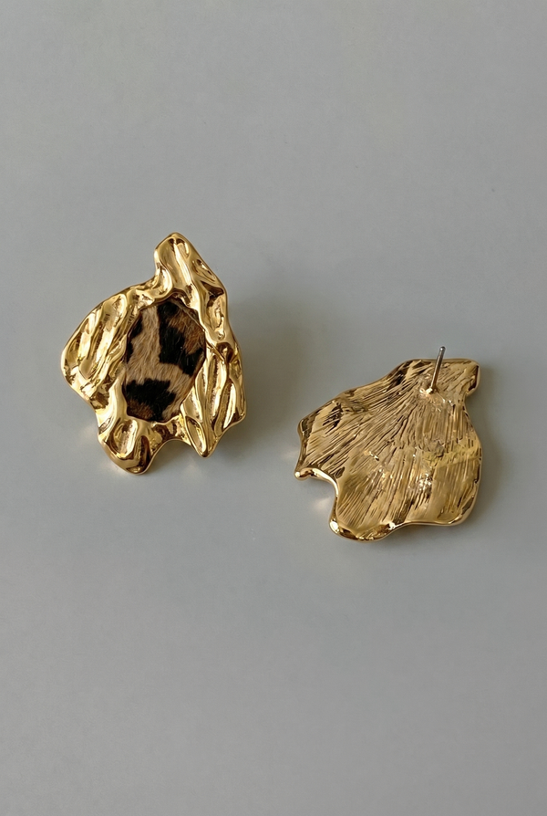 Gold leaf-shaped earrings on a gray background