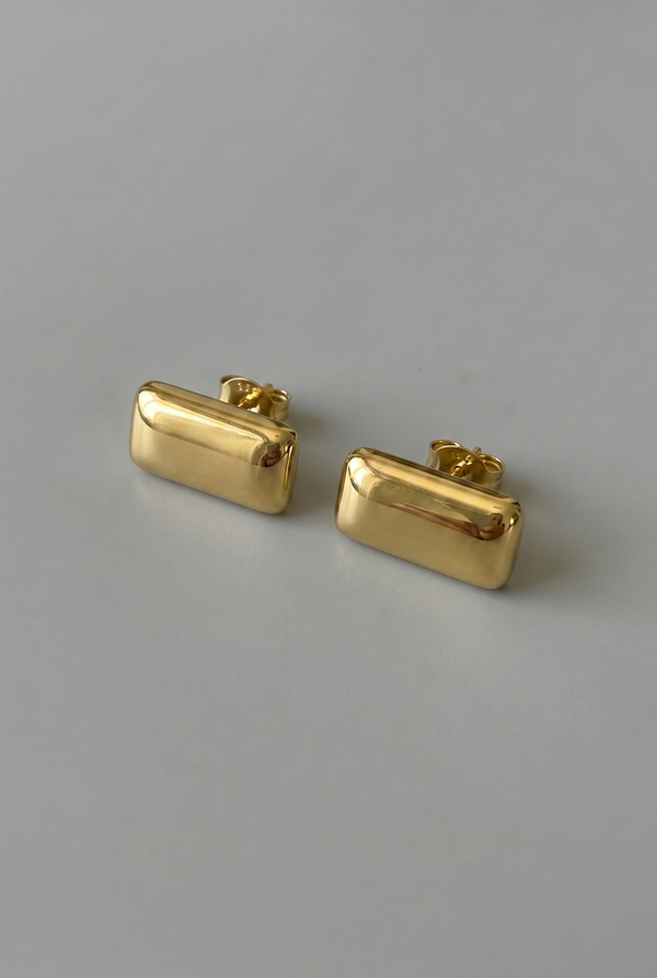 Pair of gold rectangular earrings on a gray background