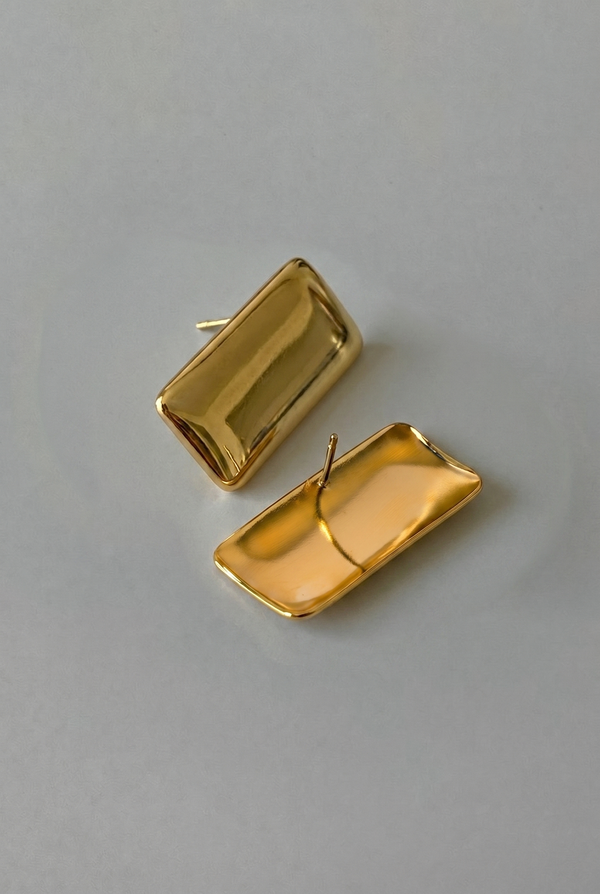 Gold rectangular earrings on a gray background