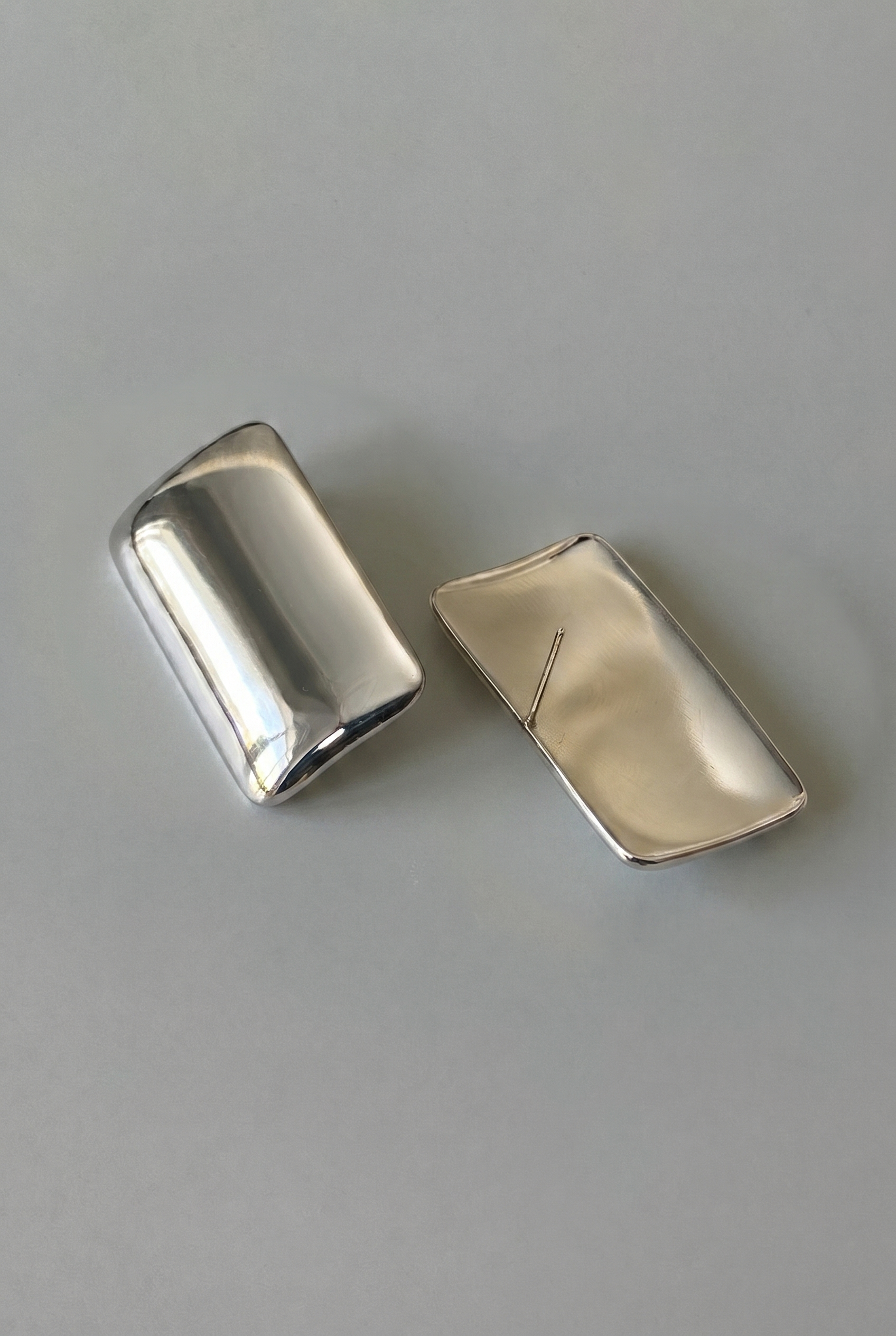 Two silver rectangular objects on a gray background