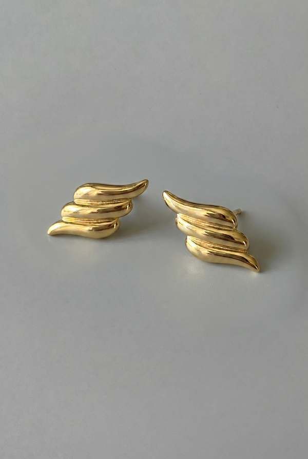 Gold wing-shaped earrings on a gray background