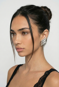Woman with styled hair and silver earrings against a white background