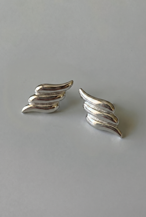 Pair of silver wing-shaped earrings on a gray background