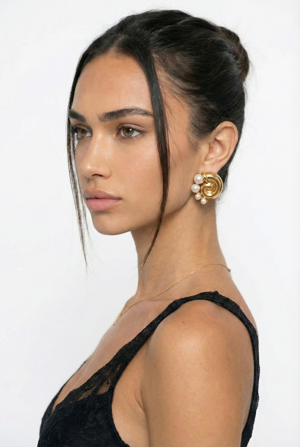 Woman wearing gold earrings with a plain background