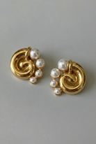 Gold earrings with pearl beads on a gray background