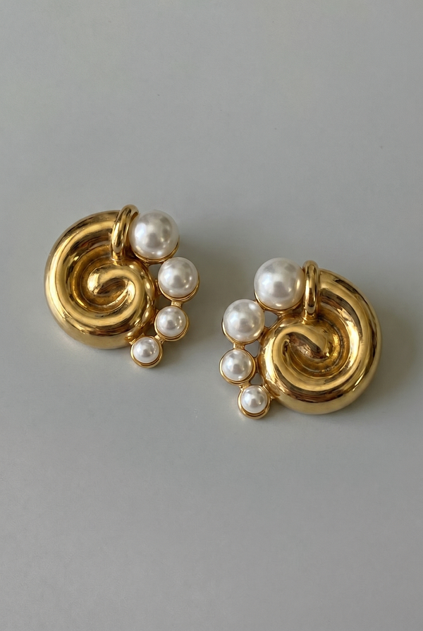 Gold earrings with pearl beads on a gray background