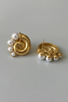 Pair of gold earrings with pearl accents on a gray background