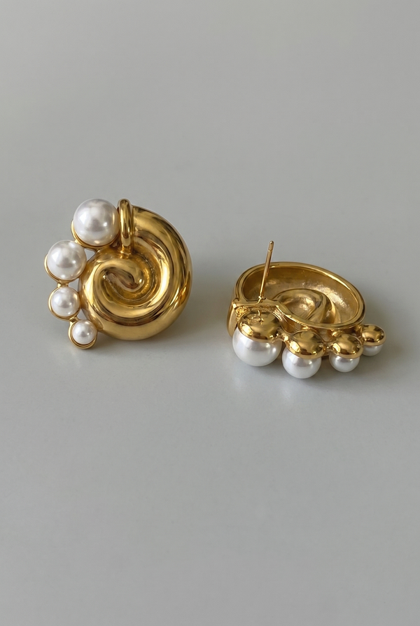 Pair of gold earrings with pearl accents on a gray background