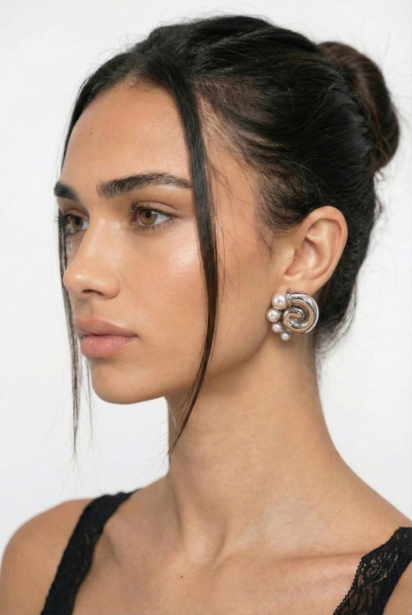 Woman with styled hair and hoop earrings against a white background