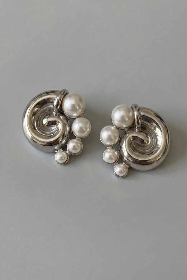 Silver earrings with pearl-like beads on a gray background