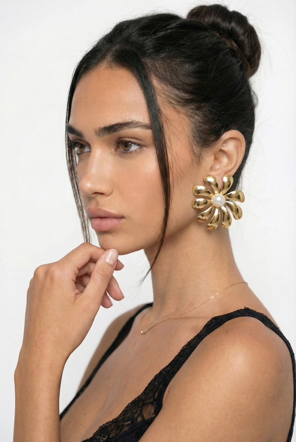 Woman wearing gold floral earrings with a neutral background