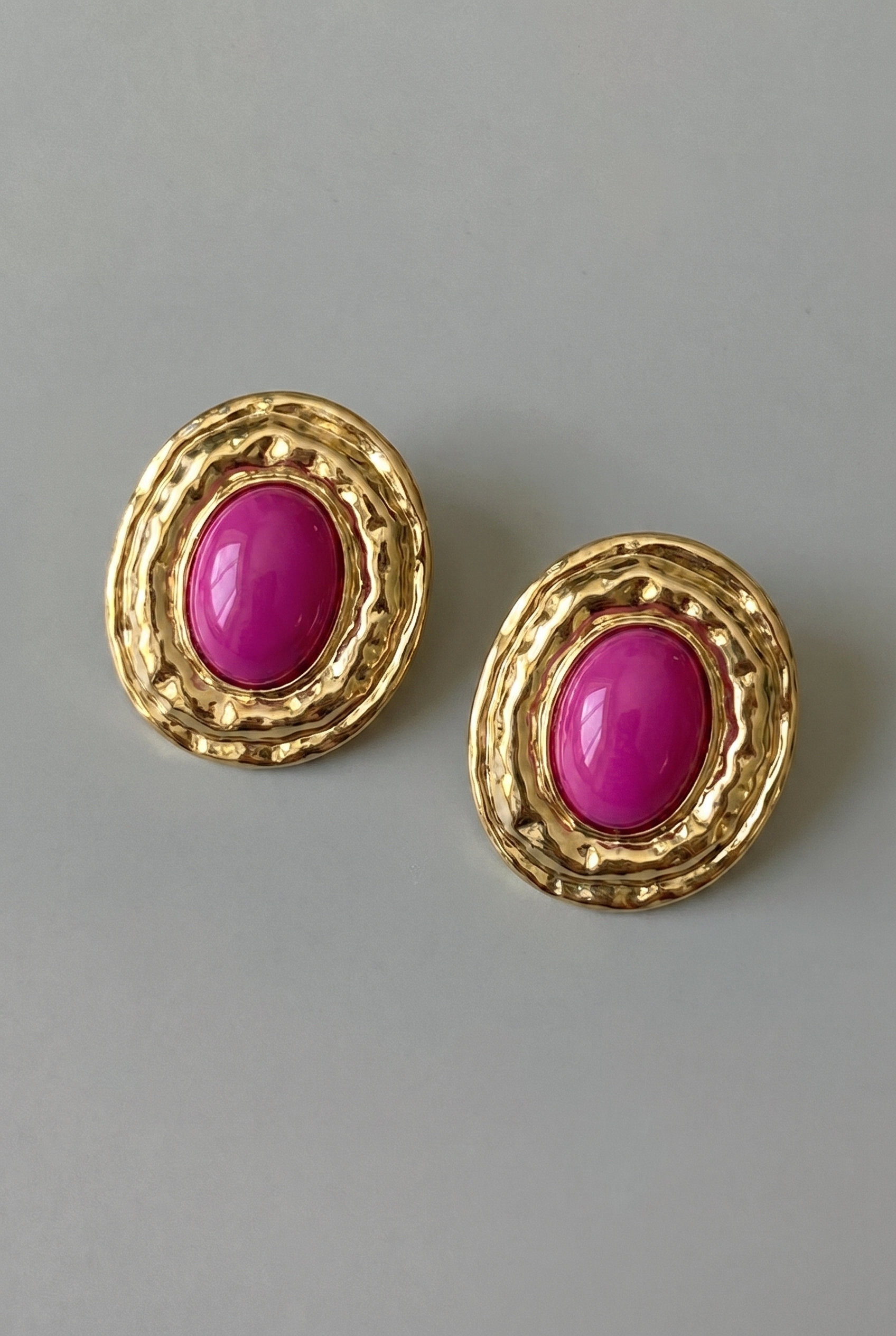 Gold earrings with pink gemstones on a gray background