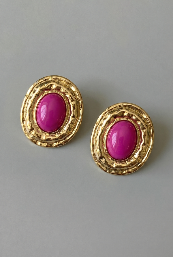Gold earrings with pink gemstones on a gray background