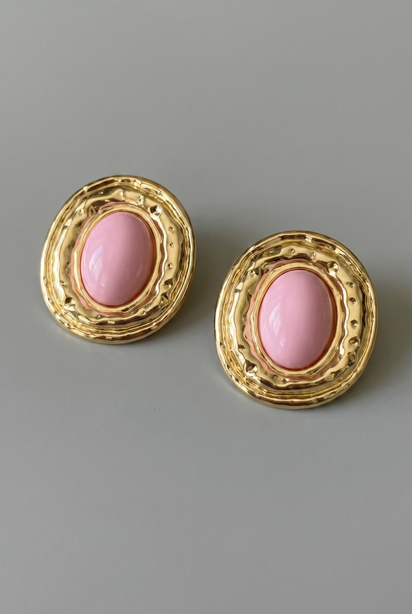Pair of gold earrings with pink stones on a gray background