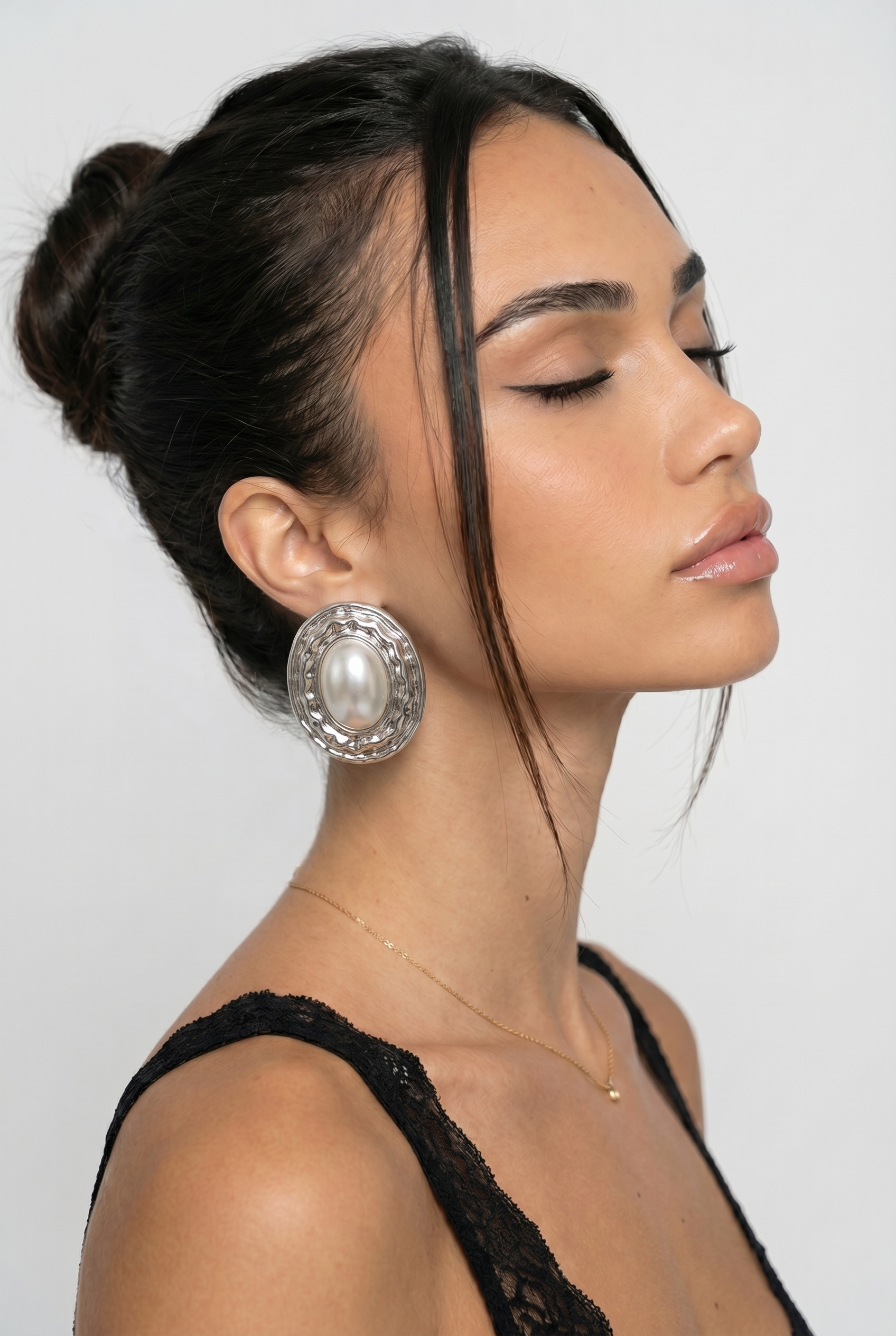 Woman wearing large pearl earrings against a plain background