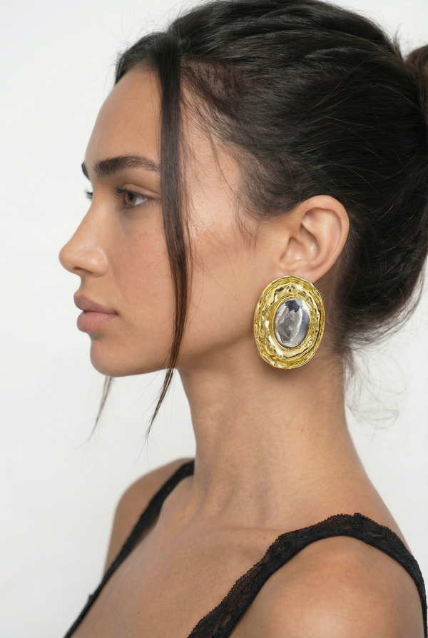 Woman wearing gold hoop earrings with a white background