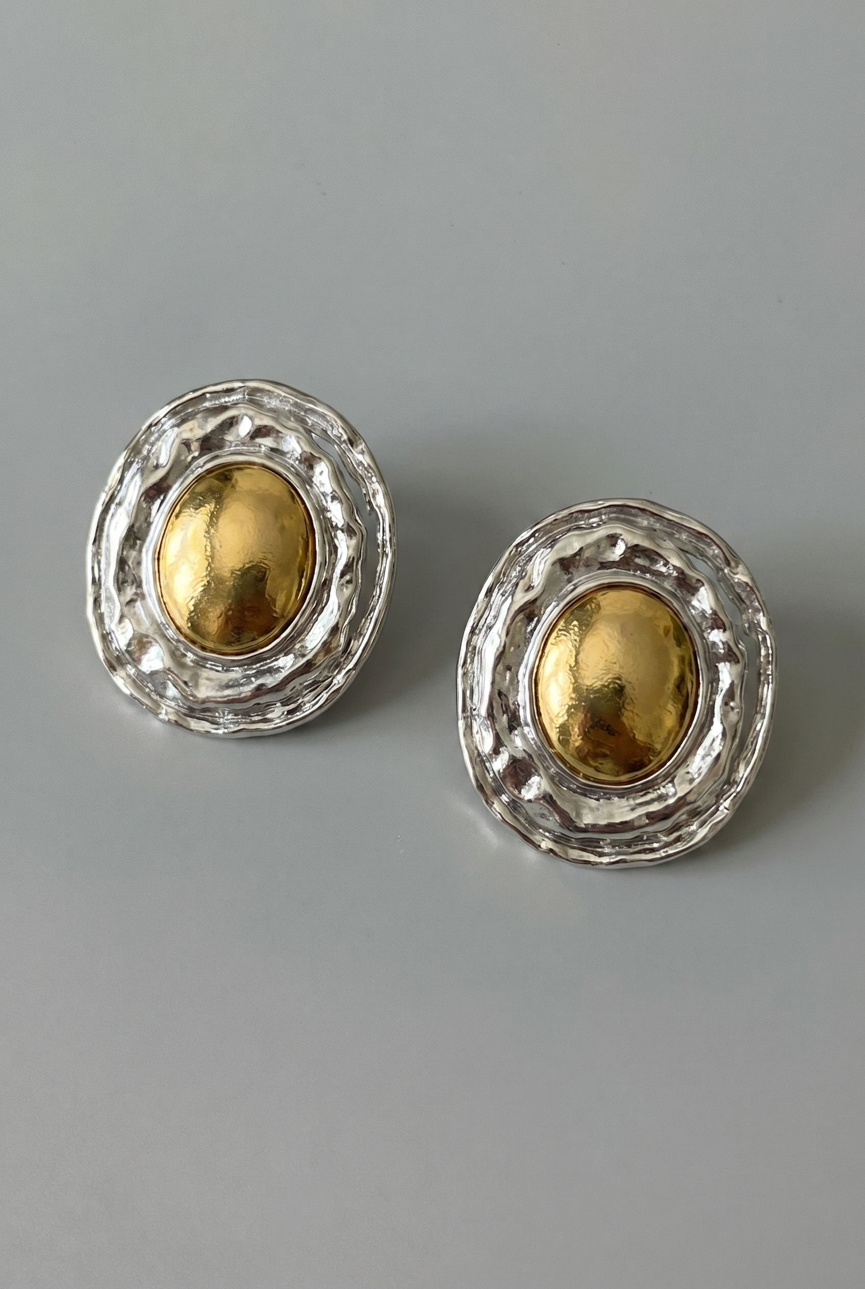 Pair of gold and silver earrings on a gray background