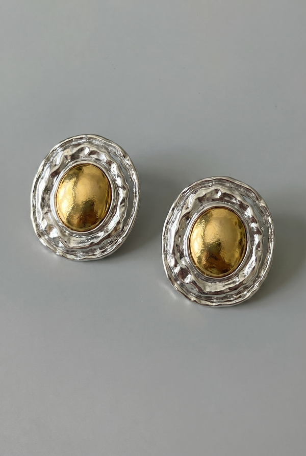 Pair of gold and silver earrings on a gray background
