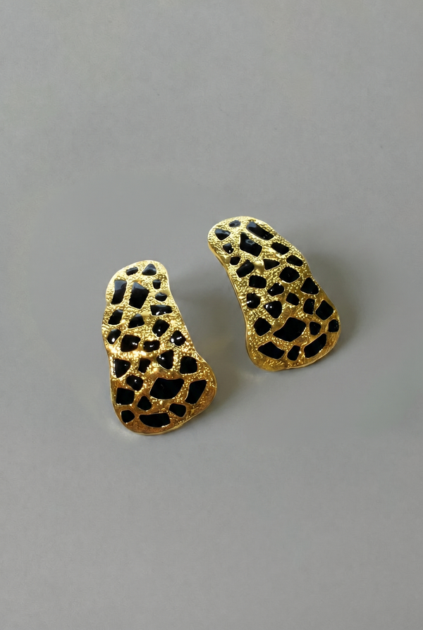 Gold and black textured earrings on a gray background