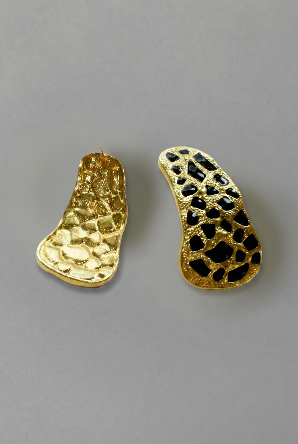Two gold earrings with textured designs on a gray background