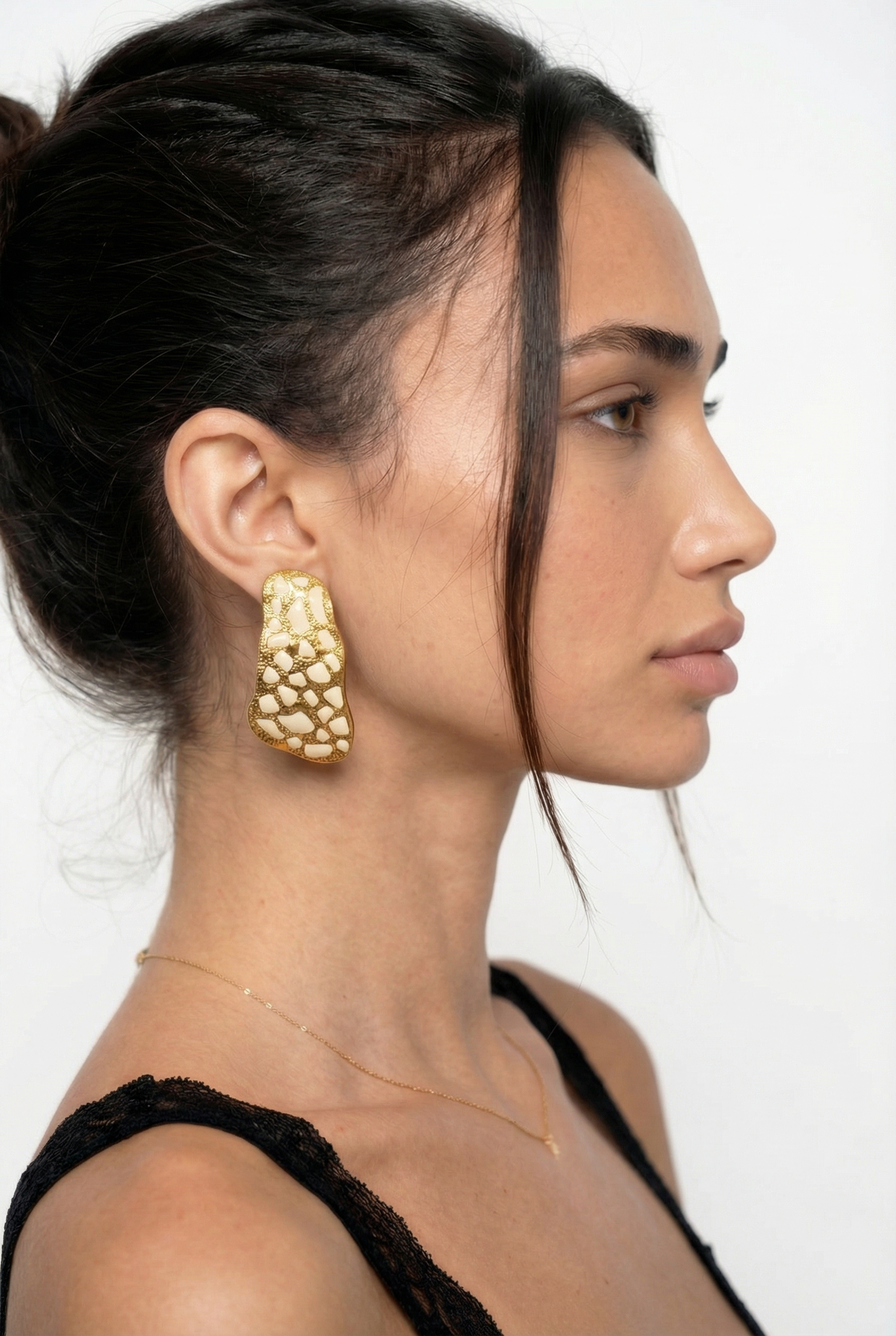 Woman wearing gold earrings with a plain background