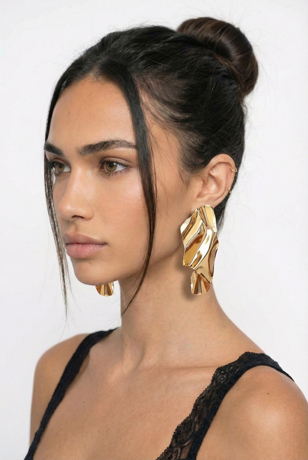 Woman wearing gold earrings with a plain background