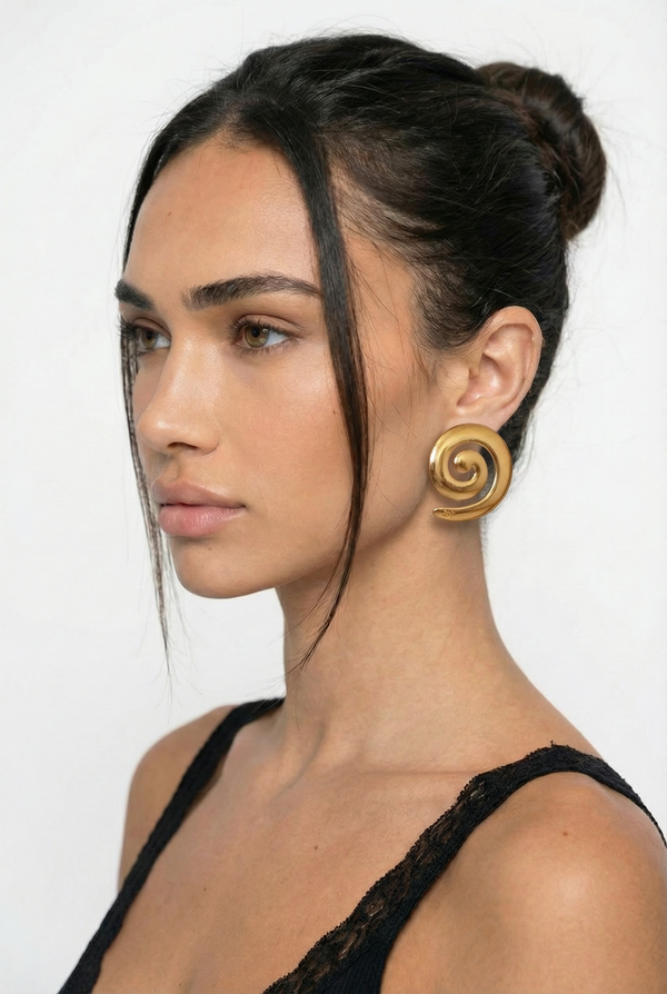 Woman wearing a gold spiral earring against a white background