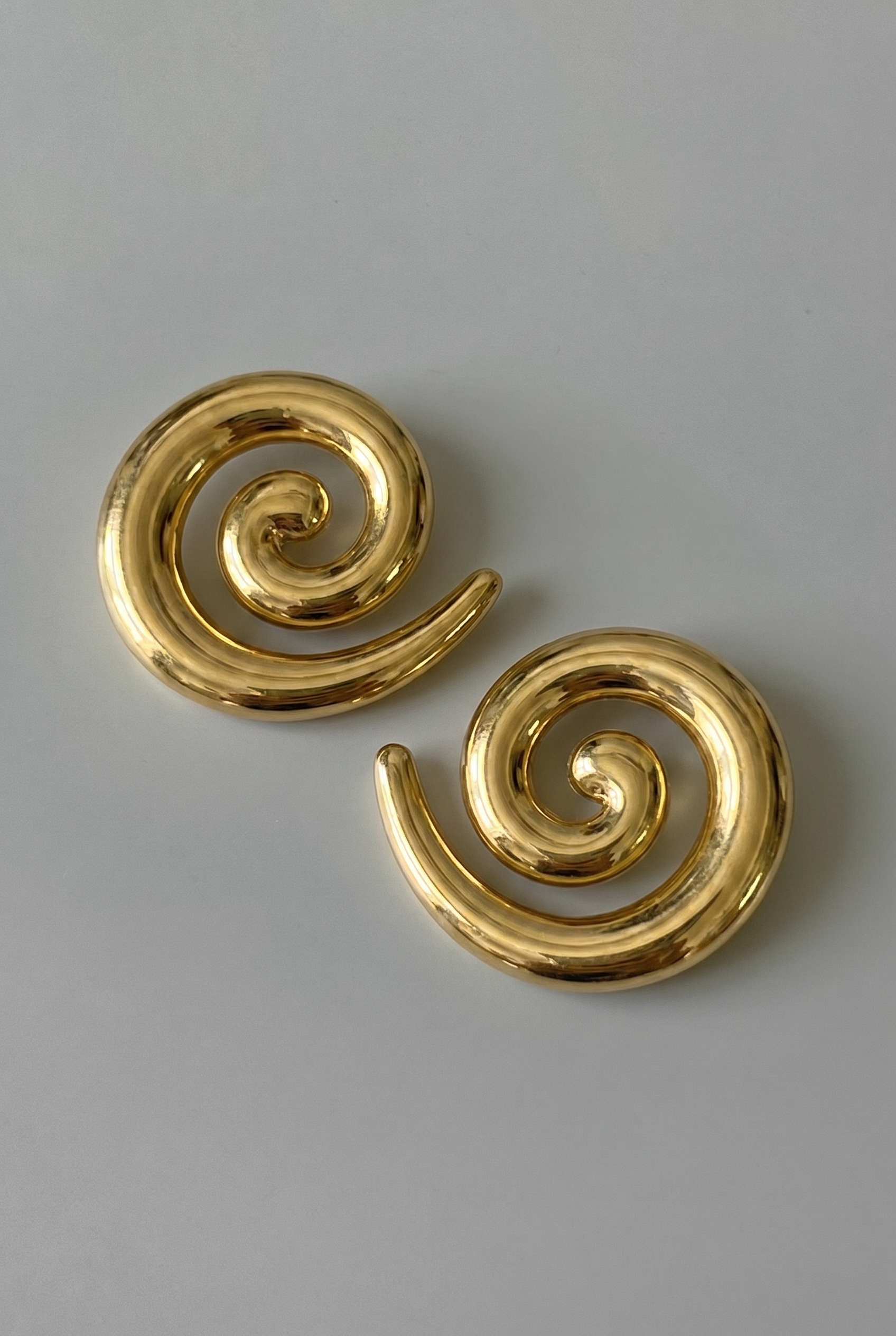 Pair of gold spiral earrings on a gray background