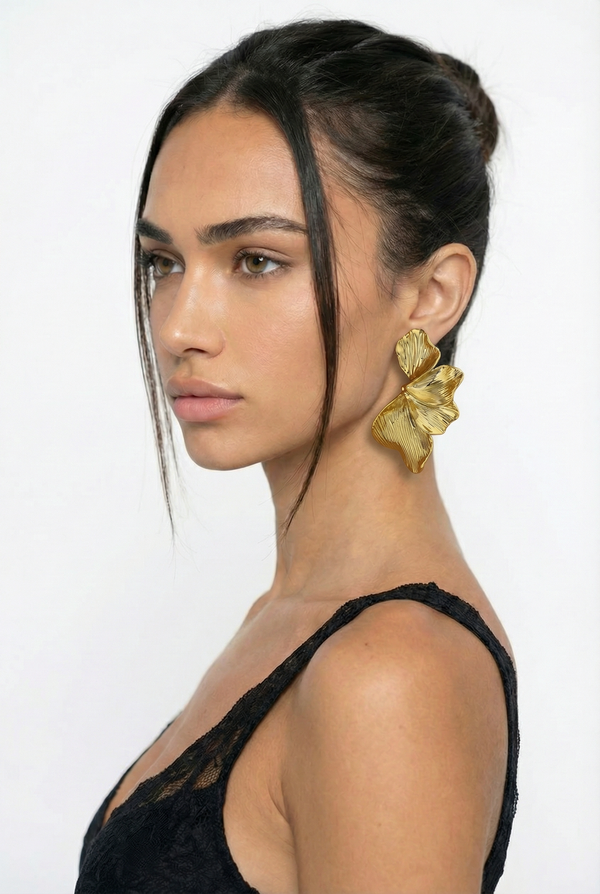 Woman wearing gold butterfly earrings with a plain background