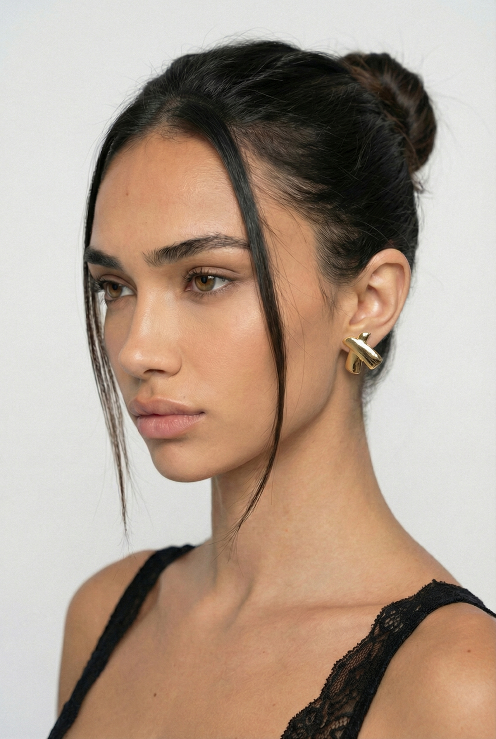 Woman wearing a gold earring with a plain background