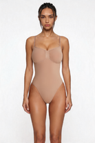 Woman wearing a beige shapewear bodysuit against a white background